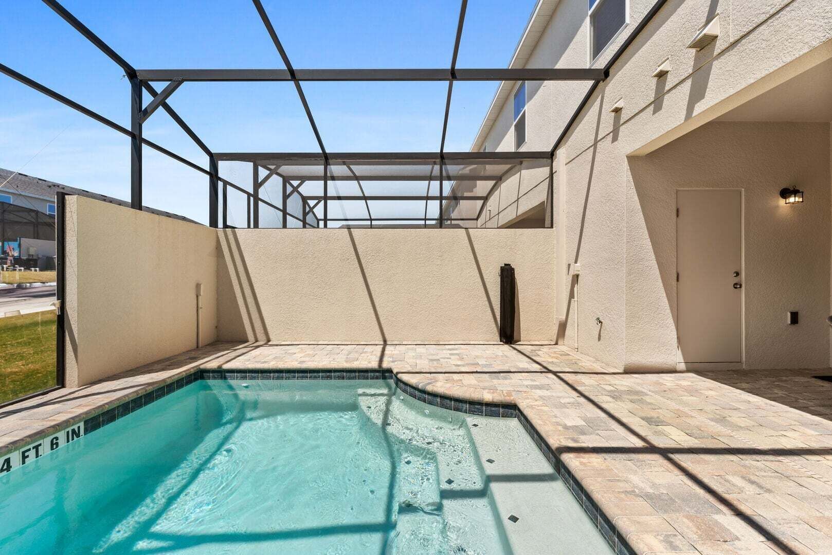 Ein Swimmingpool mit klarem, blauem Wasser, umgeben von einer Pergola und einer Steinterrasse.