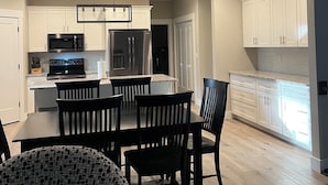 A modern kitchen with white cabinets, a dining area with black chairs, and a patterned sofa. - Spacious 4-bedroom home in a beautiful neighborhood on the edge of town (Dubuque)