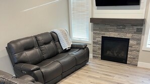 A living room with a sectional sofa, a fireplace, and a flat-screen TV mounted above the fireplace. - Spacious 4-bedroom home in a beautiful neighborhood on the edge of town (Dubuque)