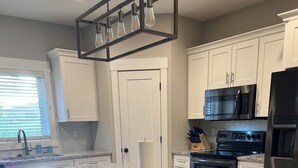 A kitchen with a granite countertop, white cabinets, a stainless steel refrigerator, and a built-in oven. - Spacious 4-bedroom home in a beautiful neighborhood on the edge of town (Dubuque)