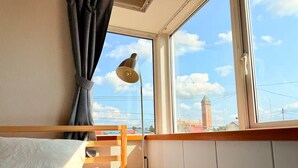 A bedroom with a bed, a window with a view of a tower, and a lamp. - Sol Stay | Patchwork Road Lavender Summer | Blue Pond & Shirogane Hot Springs (20 minutes) | Detached House in the City with Garage (美瑛町)