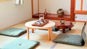A traditional Japanese room with tatami flooring, a low table with a tray of tea utensils, cushions, and a small wooden stool. - Sol Stay | Patchwork Road Lavender Summer | Blue Pond & Shirogane Hot Springs (20 minutes) | Detached House in the City with Garage (美瑛町)
