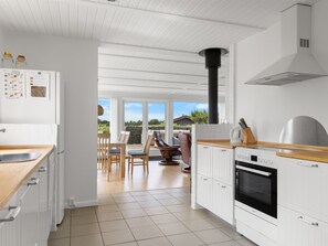 A modern kitchen with white cabinets, a built-in oven, and a view to an outdoor patio area.