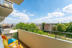 Ein Balkon mit Blick auf eine Stadtlandschaft, darunter Gebäude und Bäume.