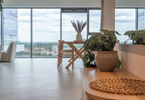 A modern interior with a large window, a wooden table, and a potted plant.
