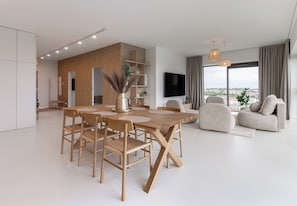 Un salon moderne avec un coin repas, de grandes fenêtres et une vue sur la ville.