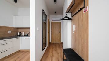 A modern kitchen with white cabinets, a wooden floor, and a black bench.