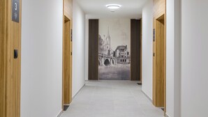A hallway with wooden doors, a wall mural, and a tiled floor. - Crocus Boutique Apartment #2 (Oświęcim)