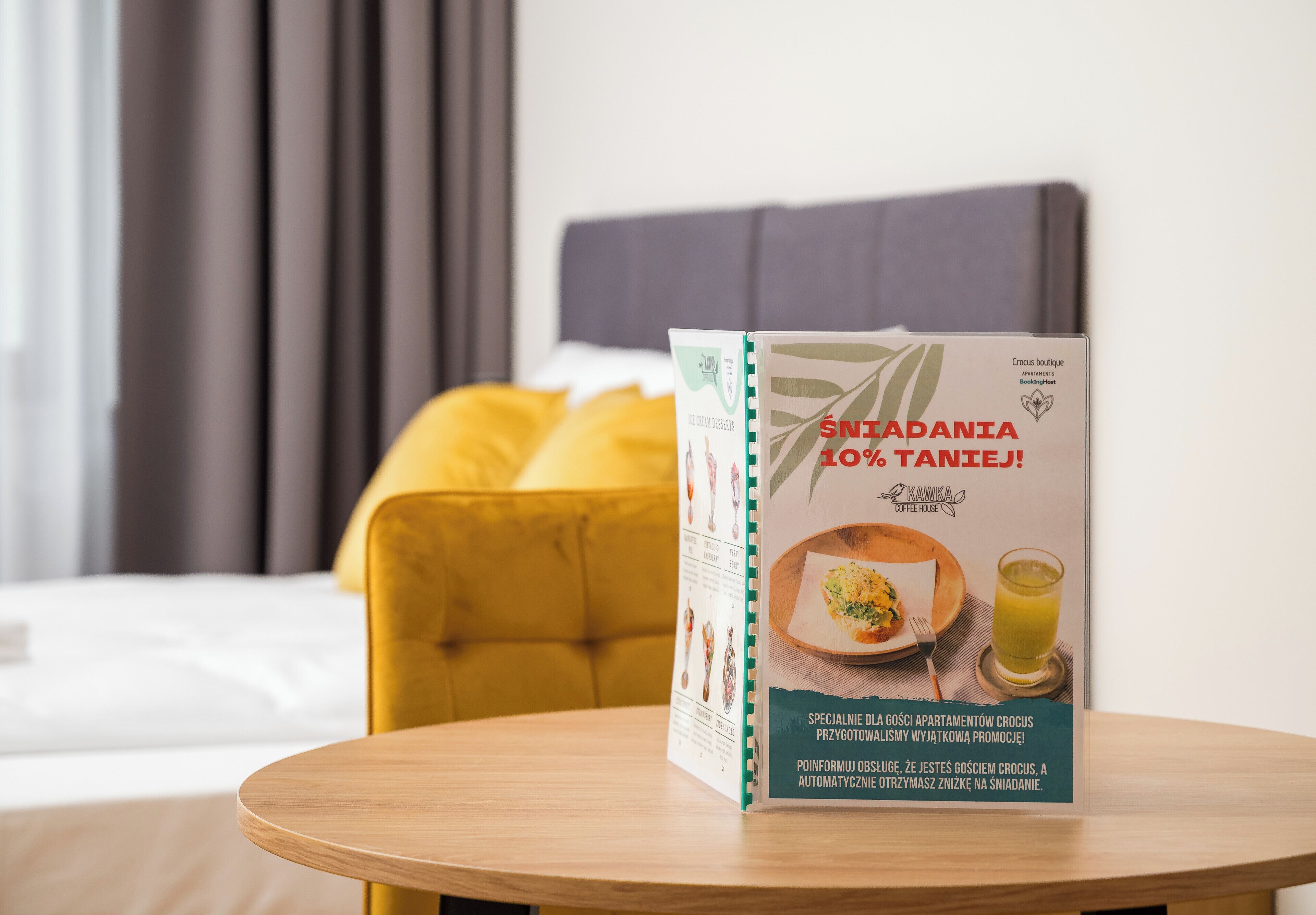 Un folleto sobre una mesa en una habitación de hotel, con una cama y un cabecero amarillo.