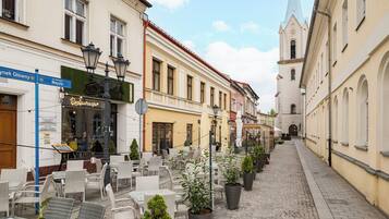 A cobblestone street with outdoor seating, a church, and buildings with signage.