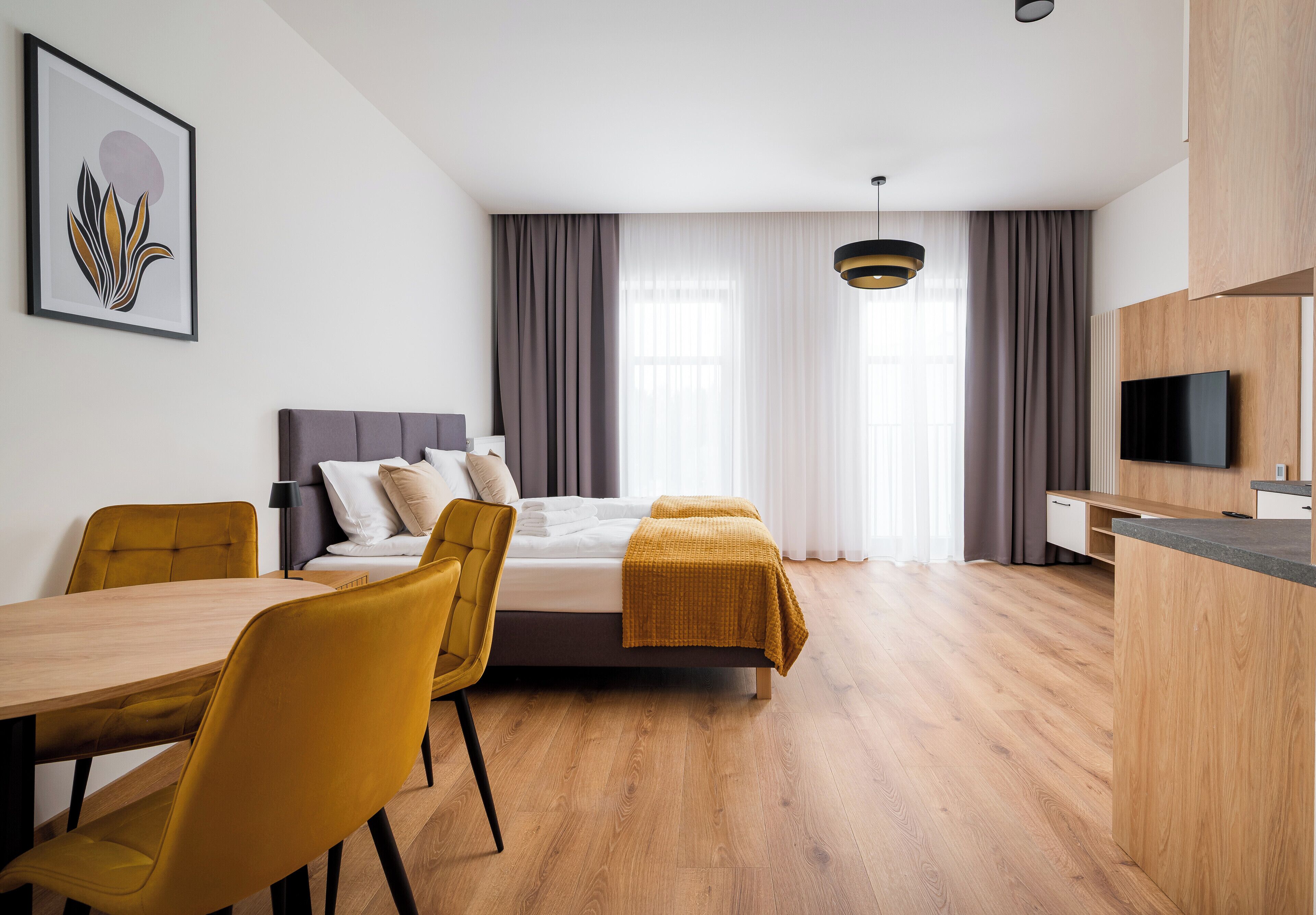 A modern hotel room with a bed, a desk, a chair, and a television.