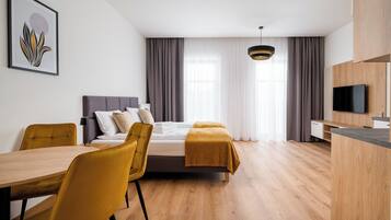 A modern hotel room with a bed, a desk, a chair, and a television.