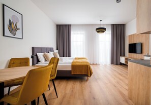 A modern hotel room with a bed, a desk, a chair, and a television. - Crocus Boutique Apartment #3 (Oświęcim)