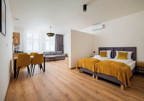 Ein modernes Hotelzimmer mit Bett, Sofa, Essbereich und Küche.