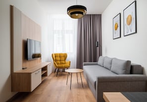 Una sala de estar moderna con un sofá, un sillón amarillo, un televisor y obras de arte en la pared.