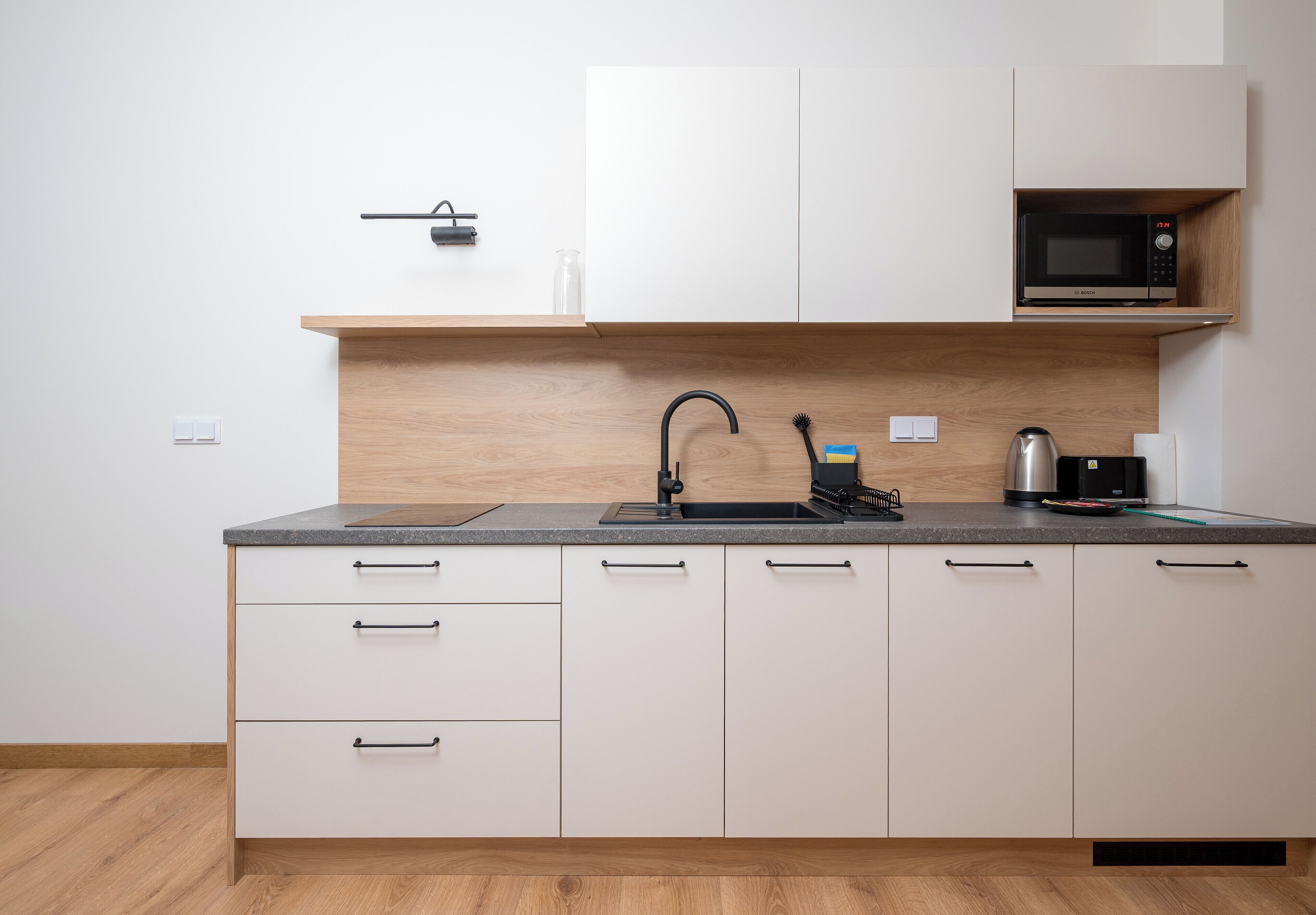 Een keuken met een spoelbak, magnetron en kastjes.