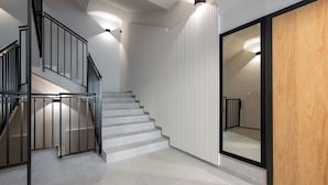 Un escalier avec une rampe noire, des murs blancs et une porte en bois.