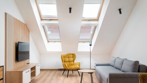 Ein modernes Schlafzimmer im Loft-Stil mit Dachfenstern, einer Couch, einem gelben Sessel und einem Fernseher.