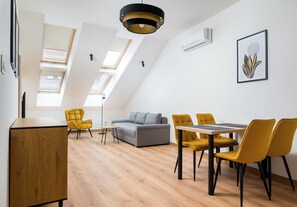 A modern interior with a dining area, sofa, and skylights.