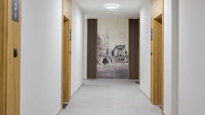 Un pasillo con puertas de madera, un mural en la pared y piso de baldosas.