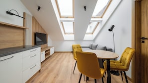 Una cocina moderna con televisor, armarios de madera y un comedor con mesa y sillas.