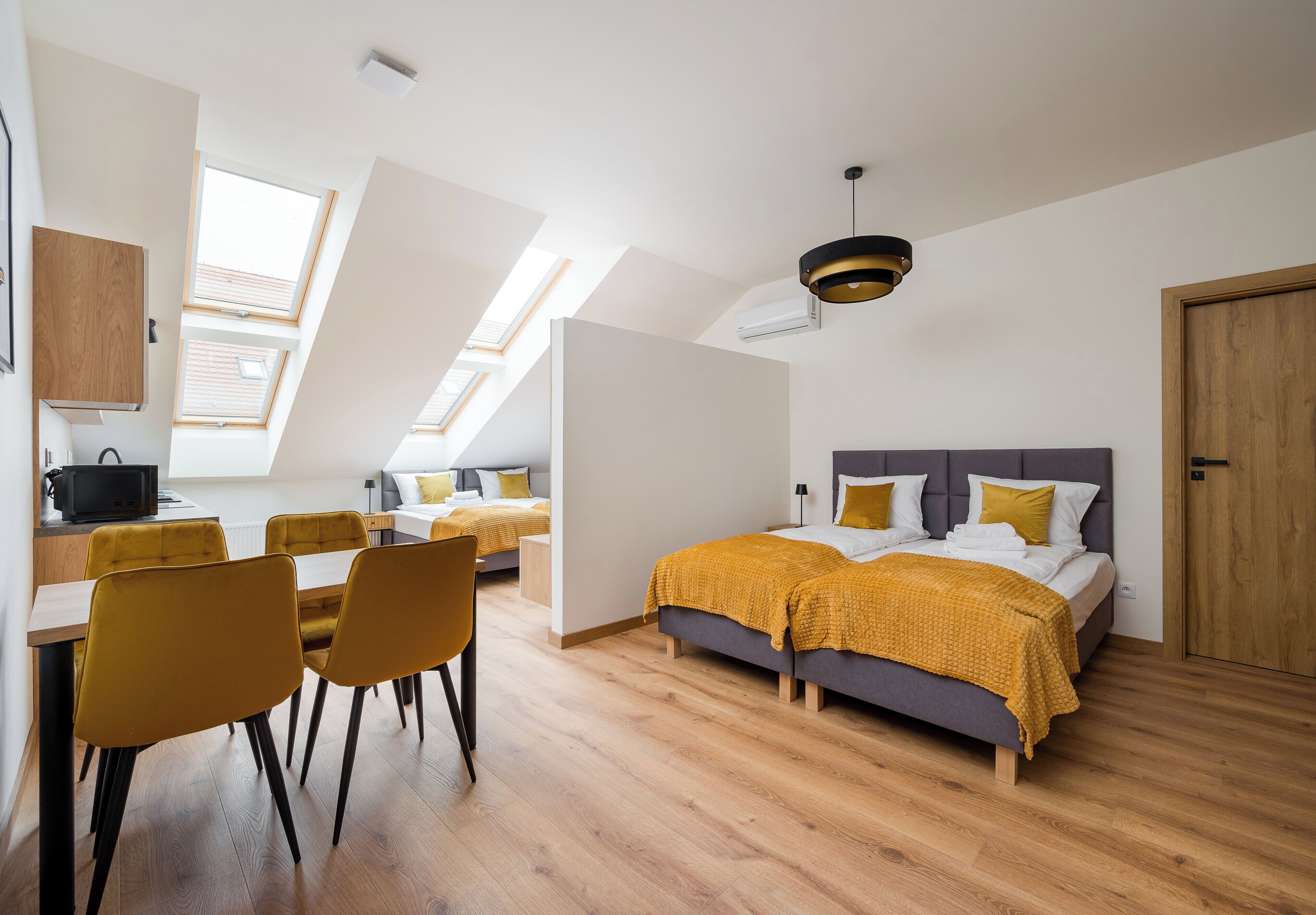 Um quarto moderno com cama, escrivaninha e cadeiras, além de um claraboia sobre a cama.