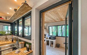 Eine moderne Küche mit Spüle, Arbeitsplatte und Blick ins Freie durch große Fenster.