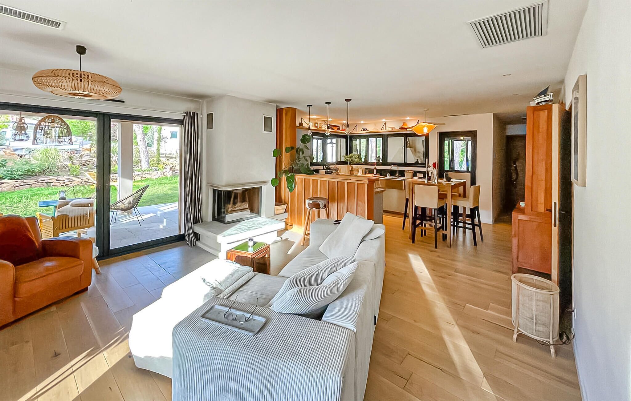 A modern living room with a sofa, dining area, and a fireplace.
