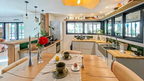 A modern kitchen with wooden countertops, a dining table set with tea cups, and large windows providing natural light. - 3 bedroom gorgeous home in Plan d'Aups-Sainte-Bau (Plan d'Aups-Sainte-Bau)