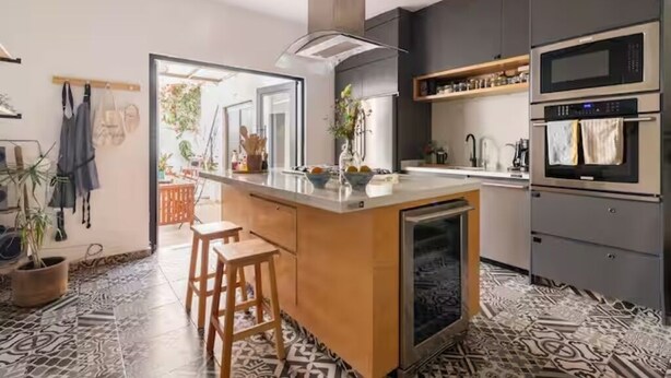 A modern kitchen with a central island, built-in ovens, and a patterned floor.
