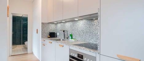 A modern kitchen with white cabinets, a granite countertop, and a built-in oven.
