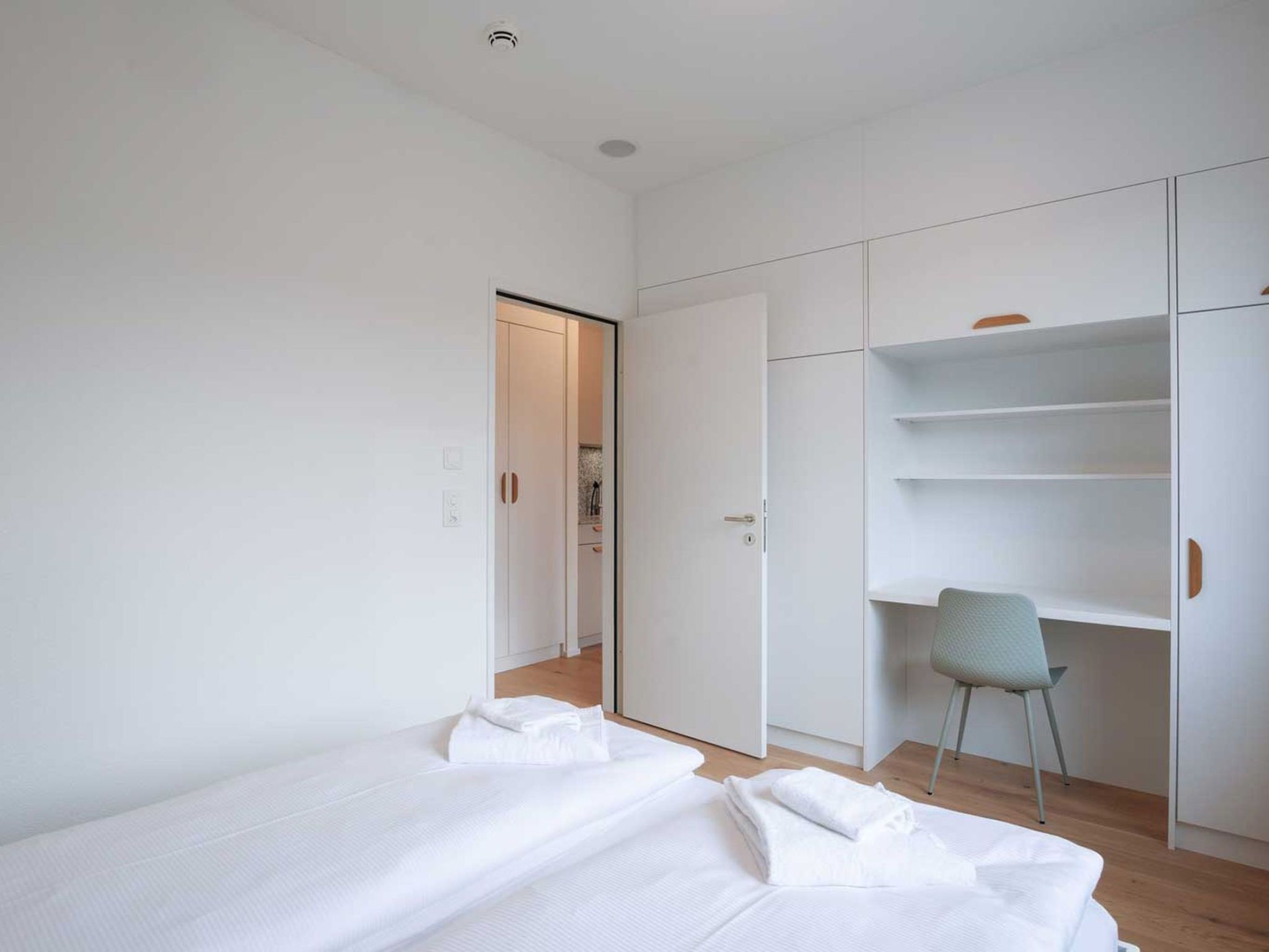 A minimalist bedroom with a bed, a chair, and a wardrobe.