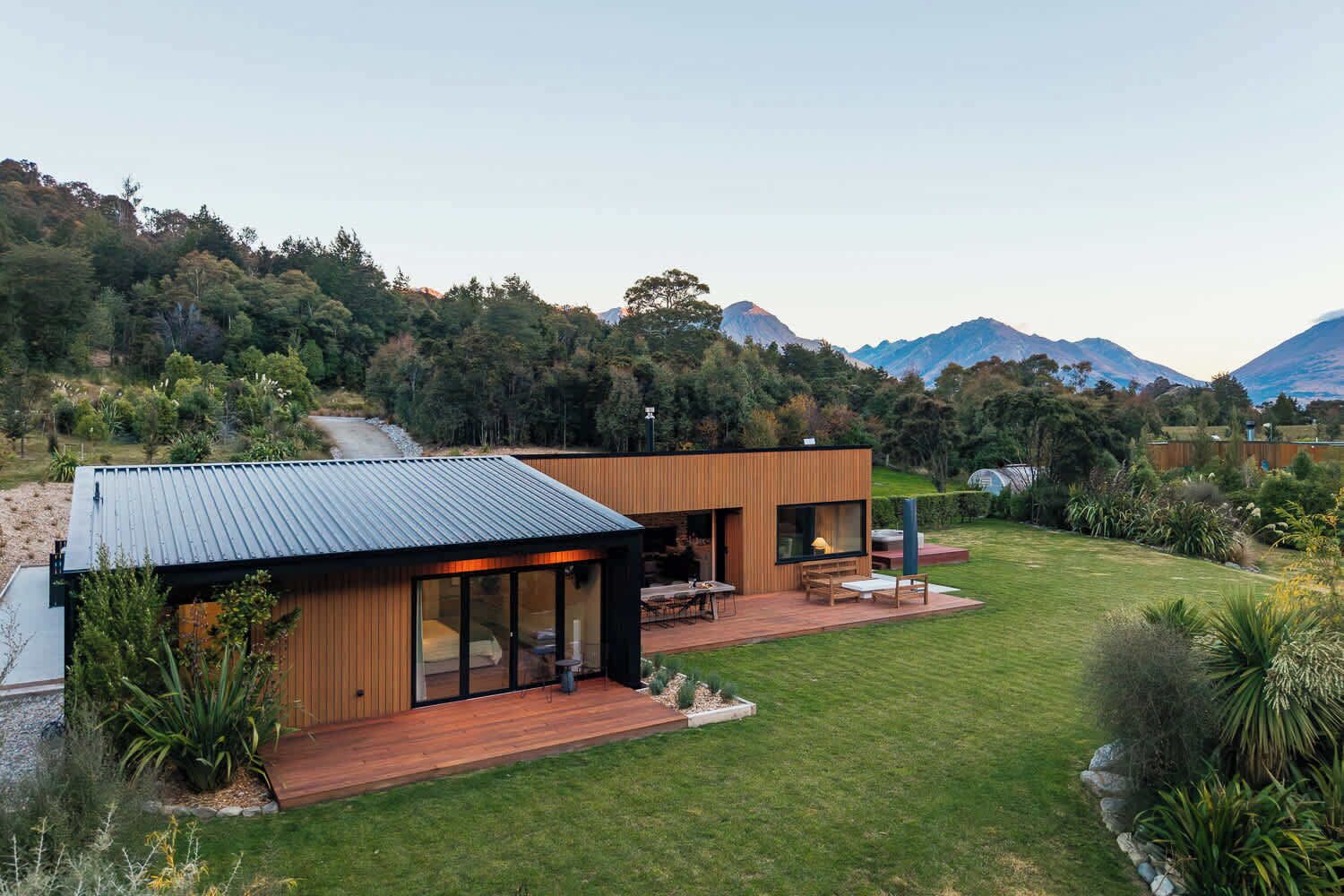 Une maison moderne dotée d’une terrasse, de grandes fenêtres et offrant une vue sur les montagnes.
