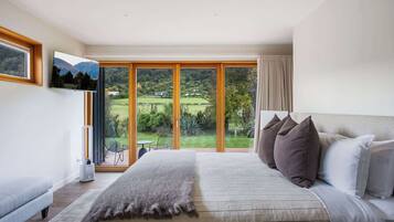 Une chambre avec un grand lit, une télévision et une vue sur un jardin et des montagnes.