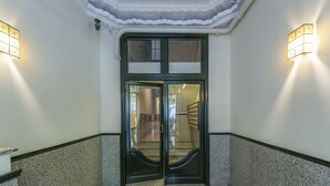 Ein doppeltüriger Eingang mit Glasfenster, Teppichboden und einer Wandleuchte.