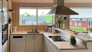 Una cocina moderna con un ventanal grande, estufa integrada y un lavamanos.