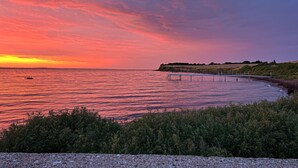 Un atardecer sobre un cuerpo de agua tranquilo con un muelle que se adentra en el agua.
