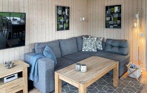 A modern living room with a grey sofa, a wooden coffee table, and abstract art on the walls.