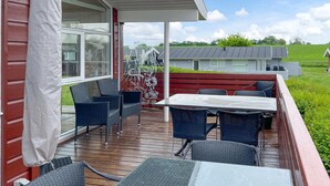 Un patio al aire libre cubierto con muebles de mimbre, una mesa y una valla decorativa.