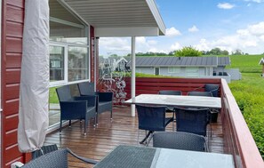 Eine überdachte Terrasse im Freien mit Korbmöbeln, einem Tisch und einem dekorativen Zaun.