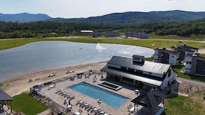 Ein Resort mit Schwimmbad, Liegestühlen und Blick auf einen See und Berge.