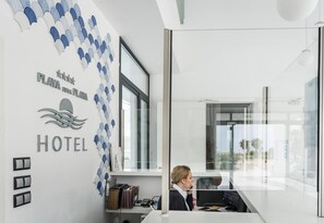 A hotel reception desk with a modern design, a large window, and a wall with a wave pattern. - Playa de la Plata (Tarifa)