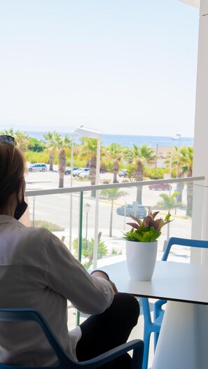 Una persona seduta a un tavolo con vista su un parcheggio e palme.
