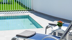 Area piscina con una piscina blu trasparente, un recinto bianco e una sedia a sdraio con un asciugamano.