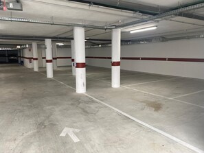 A parking garage with white pillars, red stripes, and white directional arrows on the floor. - Playa de la Plata (Tarifa)