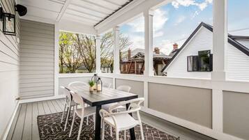 A covered patio with a table and chairs, a patterned rug, and a view of neighboring houses.