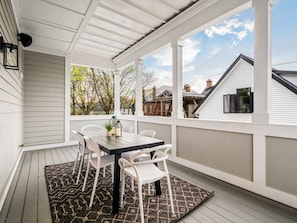 A covered patio with a table and chairs, a patterned rug, and a view of neighboring houses. - Chateau in the Village - Luxury New Build 3BD/5BA (Columbus)