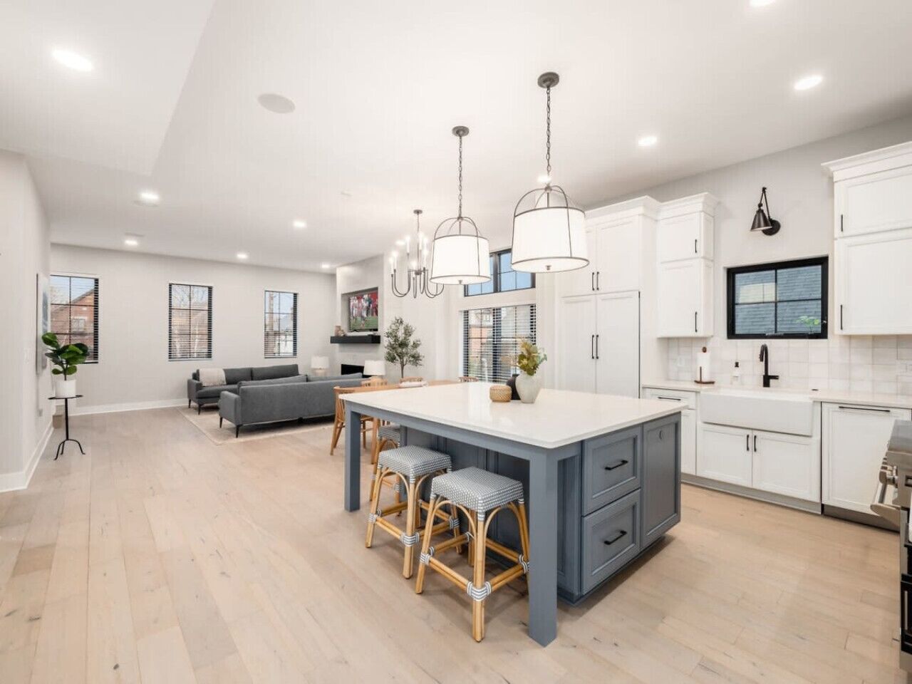 A spacious kitchen with a central island, bar stools, and a dining area with a sofa.