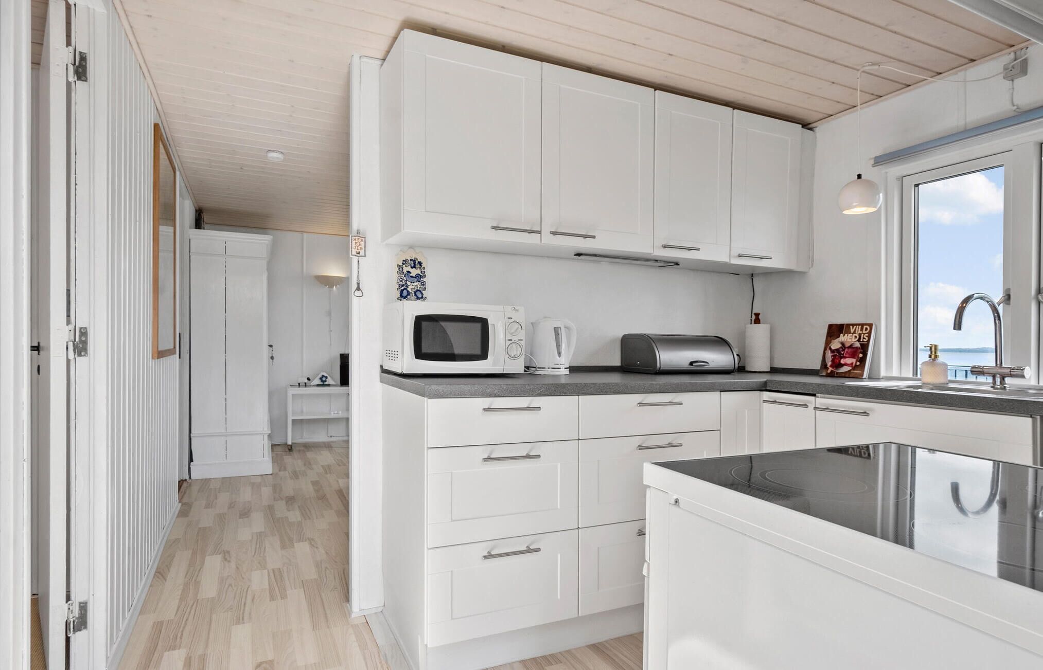 Une cuisine compacte avec des meubles blancs, un four à micro-ondes, une bouilloire et un grille-pain.