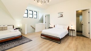 Ein modernes Schlafzimmer mit zwei Betten, einer Chandelüster, einer Treppe und Blick ins Freie.